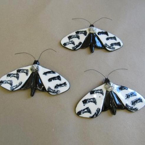 Three identical pottery moths with white striped wings