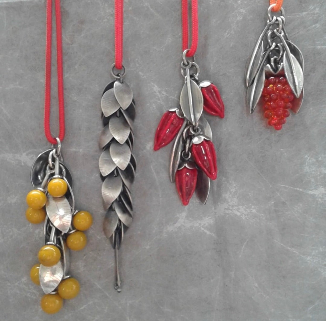 Four necklaces in a row made of silver with different coloured beads